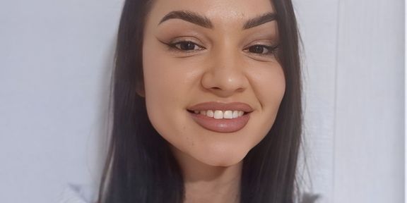 Nasmejana devojka u beloj majici ispred bele jednobojne pozadine