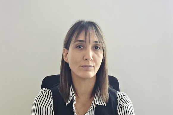Žena sedi na stolici ispred jednobojne bele pozadine
