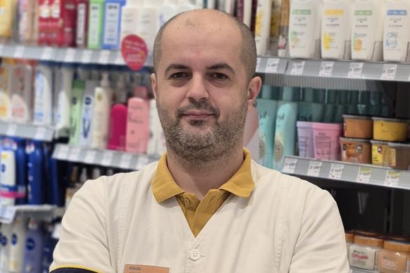 Kolega stoji pored polica sa proizvodima u dm prodavnici