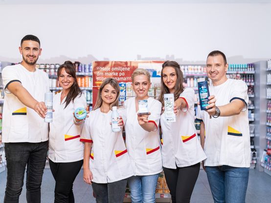 Koleginice i kolege pokazuju dm proizvode u prodavnici