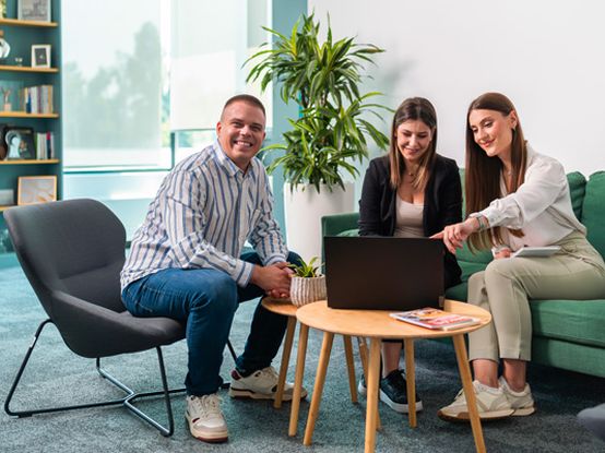 Kolega i dve koleginice sede u kancelariji za laptopom