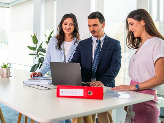 Dve koleginice i kolega rade zajedno na laptopu